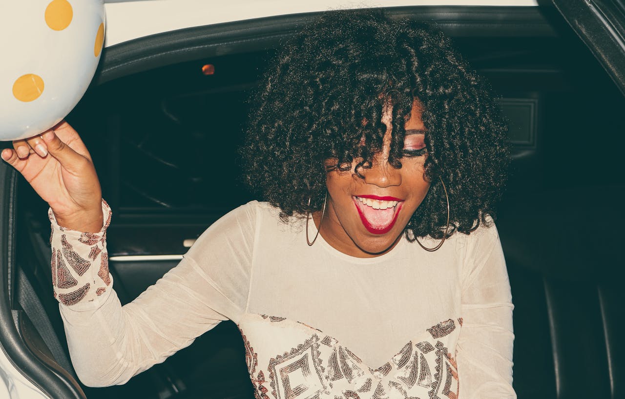 A happy young woman with curly hair enjoying a night out in a stylish outfit.